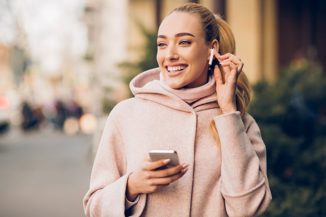 Millennial woman enjoying music in airpods, walking in city